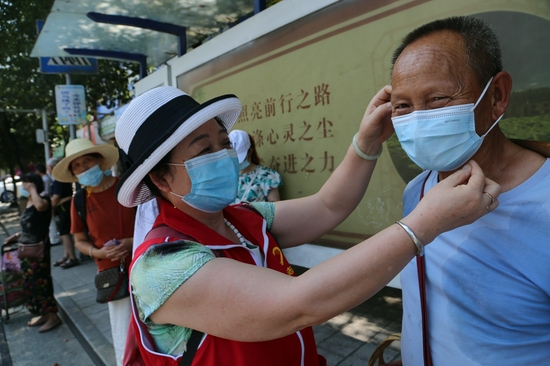志愿者帮助菜农佩戴好口罩上车。